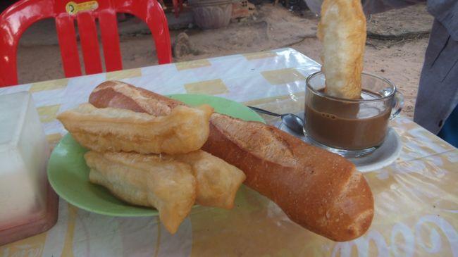 各テーブルに付け出しのように置いてある揚げパンとバケット。<br /><br />揚げパンはこうやってミルクコーヒーに浸して食べるそう。