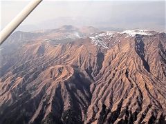 上空から見た阿蘇高岳 (1,592m)
はるか前方には，いびつな山容の杵島岳（きしまだけ，1,326m）。
前方左端には，烏帽子岳 (1,337m)。
画面中央からやや左下の隆起部は，丸山(1,187m)。
(撮影日時 2018/02/24 14:46)