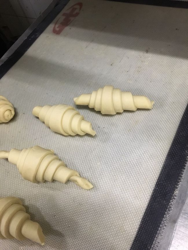 これ、クロワッサンです。<br />バターと生地を何層にも練りこんでサクサクのクロワッサンに仕上げます。<br /><br />この成形は簡単そうだな、と思っていたらシェフから<br />「あ、今のは良くないね」と。<br />あまりに強く生地を押し込んで丸めたのが良くなかったそう。<br />やっぱりこちらも生地は優しく成形するのがコツなんだそうです。<br /><br />パン作りって奥が深いですね。