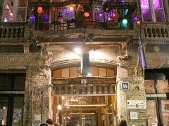 夜は旧ユダヤ人街にある廃墟バー「Szimpla Kert」へ。
ホテルで休んでいる間にGoogleMapで周囲のお店を調べていたら、非常に評価の高いお店を発見。口コミを見ていくと「Ruin bar（廃墟バー）」となんとも恐ろしげな呼び方をしている人もあり。しかも参照できる写真はいずれも立ち入り難そうなものばかり…。これは面白そうと、妻を誘って行ってみることにした。
ホテルからバス1本、暗い旧ユダヤ人街の裏路地を歩いて向かうと「Szimpla Kert」はあった。入り口では屈強なお兄さんが目を光らせて、一人一人をボディチェック。何とも入りにくい雰囲気に少し怖気付く。