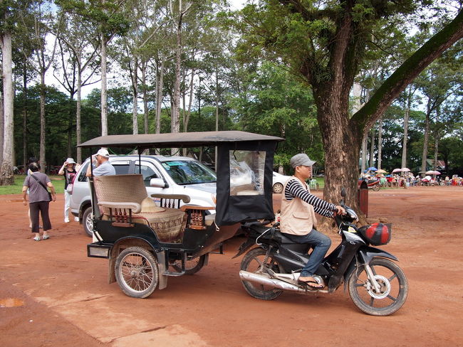 カンボジア式のトゥクトゥクであるルモ<br />よく見るとタイのトゥクトゥクや<br />インドのオートリキシャとはすこし違う<br /><br />　・タイのトゥクトゥク<br />　・インドのオートリクシャ<br /><br />リンクを見てもらえばわかるが<br />タイのもインドのも運転席と客席が<br />一体となったいわゆる『オート三輪』の<br />ような形状をしている<br />これにたいして、カンボジアのリモは<br />普通のバイクが客席を引っ張るタイプ<br /><br />この日のリモはとてもきれいだった<br />座席には王様が座るような<br />金色の布を敷いてくれていたし、<br />スコールが降ってくるとまわりをぜんぶ<br />囲うことができるような仕様になっている