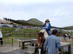 さて、天岩戸神社から阿蘇、草千里ヶ浜を目指しました。

草千里ヶ浜の駐車場はほぼ満車でしたが、数分待っただけで入れました。子供の日だったので無料でした。　駐車場の向かいに乗馬できるところがあります。

馬に乗れてご満悦の妻です。　実は茨城の乗馬クラブで初級コースを終えているので全然平気なのでした。