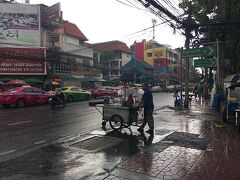 案の定、雨が降ってきた。運河を渡り、カオサン方面へとPhra Sumen通りに出たところで小走りしたが、ホテルまでまだ１０分以上かかる。というわけで RdChakrabongse Rdとソイラムブトリの交差する角にある銀行で雨宿り。目の前では、屋台を引く男がChakrabongse Rdを渡ろうとしていた。近くのホテルを位置情報にした。