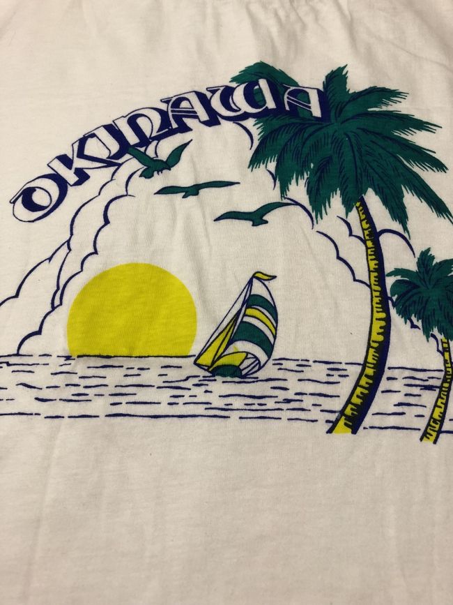今回現地で着てから捨てるTシャツ。<br /><br />自宅のクローゼットから<br /><br />発掘される。<br /><br />なん年前の地層か、不明。<br /><br />あまりの古めかしさに<br /><br />バブル白亜紀と推定。<br /><br />うん確かに昭和60年頃<br /><br />沖縄へ行ったわ…（´-`）.｡oO