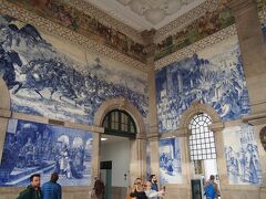 ポルト　サンベント駅
前半ダイジェスト版で、ランチを食べたマトジーニョスから１１ｋｍ程度１５分ほどでポルトのゲストハウスに到着。
ホテルでちょっと休憩後ポルト市街地。
時間も大分過ぎたけど、まずはポルト市街中心部のアズレージョで有名なサン・ベント駅へ。
普通に駅を利用する客と、駅のアズレージョを見る観光客とがすれ違いながら、人の流れもあるものの、駅舎全体に装飾されたアズレージョは確かに必見です。
色々なシーンがあり自分のお気に入りのアズレージョを見つけるのも良いかも！