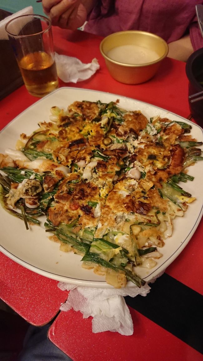 鍾路３街のチヂミ横丁的なお店で食べた海鮮葱ジョン<br /><br />写真のは、ならんでるお店のどちらの海鮮葱ジョンが解らないけど<br />道路から向かって右側のお店のジョンはカリカリで香ばしくて美味い<br /><br />向かって左側のお店も美味しいけどカリカリ感は少なめだが美味しくて珍しいマッコリの種類は凄く多いので、どちらも当たり店