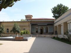 日本人墓地観光の後に訪れたのがウズベキスタン工芸博物館です。
この日の撮影料は１ドル（スムなら６０００スムなので約９０円、ガイドから徴収された料金は少し高めでした。）、といっても今日撮影料が必要なのはこの建物のみ。
現地通貨で払う方がお得なのでスムで支払いたいのですが、ガイドに支払う料金は全てドル換算、よって個人旅行の方がお得だと思います。
さてこの建物、ガイドの説明によると綿花栽培や取引で財を成したロシア商人の邸宅とのこと。華麗な王宮の装飾に魅せられ、自分の邸宅に王宮と同じく壮麗な装飾を施したそうです。元々の建物はもっと広くて現在の建物は元の建物の1/４の広さしかなく、３/4は焼失したとのこと。
さてこのロシア商人、スターリン時代に共産党政権の捕縛から逃れるために逃亡したそうです。建物はコの字型で中央の居間は確かに宮殿を彷彿させるような素晴らしい装飾の部屋でした。
帰国後旅行記を書き起こすためこの建物のことを調べると、地球の歩き方では全く違うことが書いてありました。
それには1907年に建てられたロシア公使の私邸を利用した博物館」と書かれてあったのです。
公使と商人では全く違います。どちらが正しいんだろうか？
ネットの旅行記では地球の歩き方の記事を引用したものばかり、ウズベキスタン政府観光局の記事では「ソ連時代の王族の邸宅」と書かれておりこれまた異なった記述でどれが正しいのか不明。
ガイドは国家試験に合格してなっています。そして公式マニュアルに書かれた文言を説明している訳だからガイドの説明が正しいとしてこの場は掲載しておきます。



