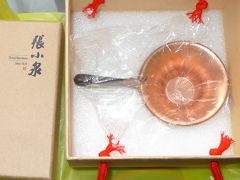 《張小泉刀剪総店：銅製の茶こし 328元》

ショーケースに鎮座していた銅製の茶こしを見せてと言うと奥から新品を何点か出してきた。
どこかが違うと思ったら取っ手の飾りが違う。

金魚はオンリーワンだと、鍵がかかった上にガムテープで蓋を固定していたショーケースからわざわざ出してもらった。
こうなったら、「やっぱりいらない」とは言えない。
