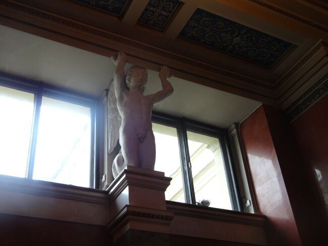 天使が無表情に持ち上げてます。上もちゃんと見ないと損です。<br />Map109<br />L.フォン・クレンツェ<br />ダヴリアのヴィーナスの間<br />彫刻の展示のために作られた1階の各室は簡素で威厳に満ちていることが特徴である。クレンツェの構想に従って、これらのホールの壁は特殊な製法《セメントと大理石の粉、そして着色剤から造られるいわゆる大理石セメント》によって作られた様々な色の上質の人工大理石で上張りされている。ダヴリアのヴィーナスの間では、古代ローマの大理石像が赤い壁によく映えて美しい。このホールの採光は、壁面上方2段に設けられた窓によって実現される。（土産本）