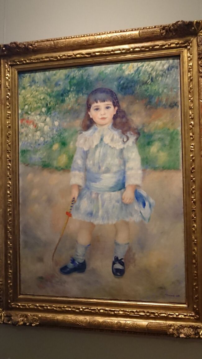 少年？？<br />P.=A.ルノワール《1841-1919》<br />小さな鞄を持った少年　1885　カンバス、油彩<br />この絵の主人公は何といっても陽光である。少年の姿を風景の中に溶け込ませ、その白い服や黄色い砂道に緑や黄、そして水色っぽい色合いを添えている。しかし、エチヤン・グジョン少年の丸い顔と黒目がちの大きな瞳、そして鮮やかでふくやかな唇は丁寧に描きこまれていて、印象はらしくない。この絵が制作された時期、ルノワールは新しい画法を模索していて、印象派の偶然性と前世紀18世紀絵画の古典的な緻密さとの統合を夢見ていた。（土産本）