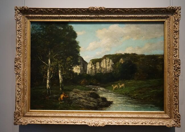 ギュスターヴ・クールベ「狩猟者のいる風景 」1873年<br />本作品は、パリ・コミューンに関わって投獄されたクールベが、スイス亡命直前に故郷オルナンを描いたものです。狩猟画はクールベの得意のジャンルの一つであった。陽光を受けた岩山を背景に、2匹の愛らしい鹿とこれを物陰で窺う漁師との間の緊張感が、みずみずしい情感に溢れた自然描写と一体となって描かれています。