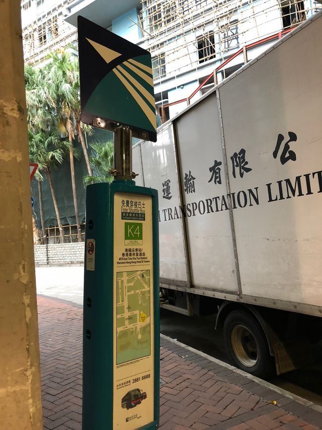 エレベーターに乗ろうとしたら、九龍駅からのシャトルバスが見えました。シャトルバスは運航しているようだったので、バスで九龍駅に行くことにしました。<br /><br />行ってしまったばかりなので１０分ほど待ちました。<br />バス停は柱の陰に隠れていました。