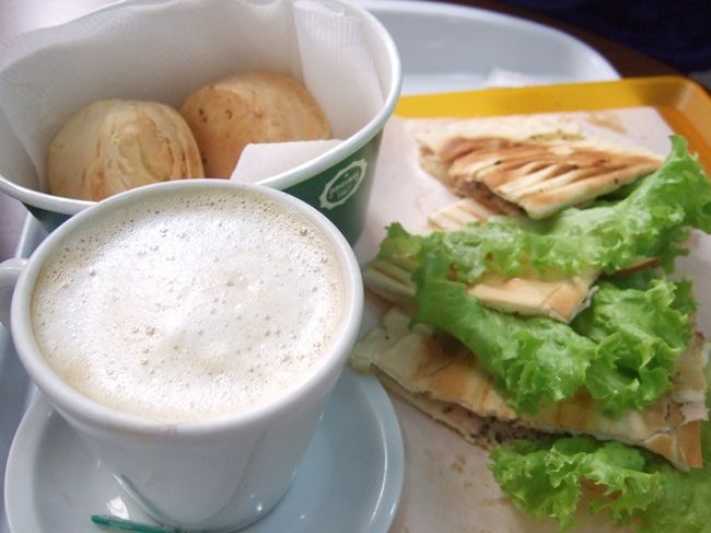 空港で簡単にランチ。ポンデケージョどこで食べてもほんっと美味♪<br /><br />今夜のホテルはギマライアンス高原の方なので、タクシーを手配。クイアバの空港で待ち合わせて試合会場まで連れていってもらい、荷物をあずけて試合を観戦し終わってから運転手と合流してホテルへむかう算段。<br /><br />今回、ブラジルは交通手段があまり整備されてないせいか、こういうタクシーサービスがけっこう充実してました。ま、安くはないですけどね。<br /><br />空港で待ち合わせてたのはホセという運転手で、合流してからこのタクシー会社にいってそこで荷物を預けてからスタジアムへいってもらう予定のはずが、きたのはホセじゃないし事務所も行かないでそのままスタジアムいくとかいうし・・・。