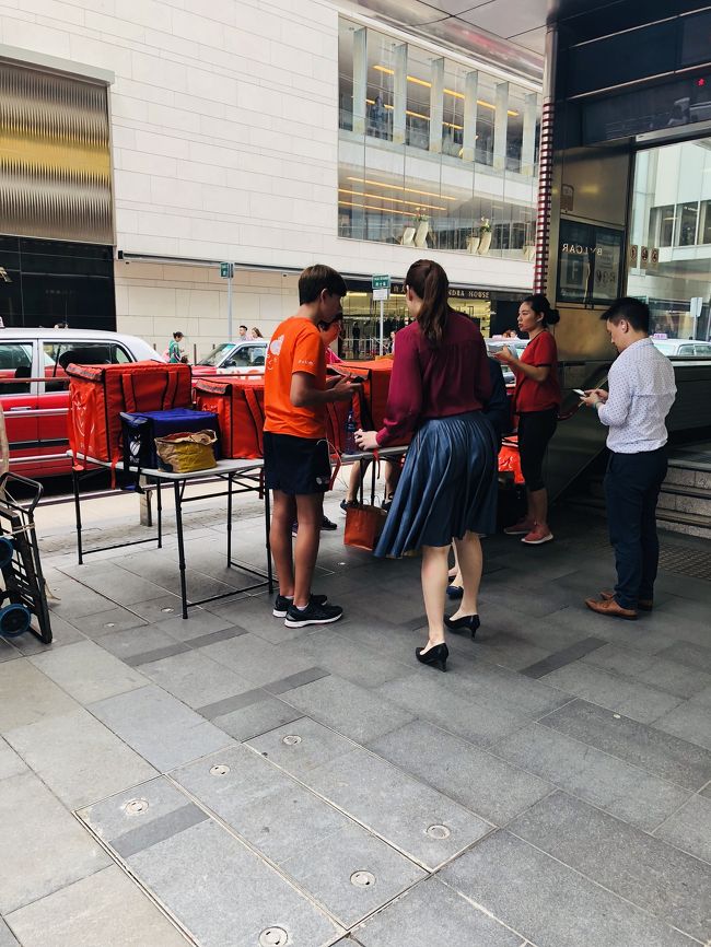 ランチの予約、引き換え場所のようです。<br /><br />予約している人はスマホを見せてランチBOXを受け取って行きます。<br /><br />どんなメニューなのかとても興味があります。<br />アジア経済の中枢地区である中環で働く方々が、ランチにどんな物を食べているのか知りたいっ！。<br /><br />「サラメシ」スタッフさん、取材して頂けないでしょうか・・。<br />