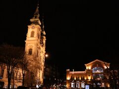 広場に面した教会の塔と商業施設の建物。