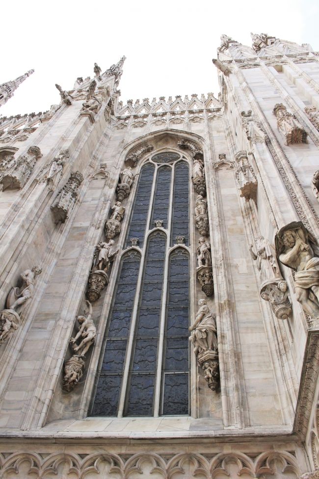 さて、ガッレリアを一回りしたあとはいよいよドゥオーモの中へ。チケットは正面向かって右側にあるチケットセンターで購入するのですが、入口で受付をすると、呼び出し番号のレシートのようなものが出てくるので、決済は番号の呼び出しを受けてから。まあまあ混雑していたので、結構待ちました。<br /><br />あ、最初買い方がよく分からずおたおたしてたからチケットセンターの写真は撮るの忘れてたな。こちらはガッレリア側の側面の写真。見上げると本当にすごいな…。