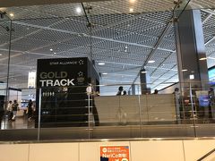 午前で仕事を切り上げ、その足で成田空港へ。出国審査のためエスカレーターで降りていきます。Gold Trackの文字を横目に。