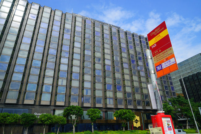 滞在の「カオルーン・シャングリ・ラ香港」です。ハーバーサイドから全景を写したものです。右サイドのオレンジ色と標識は、バス停留所です。