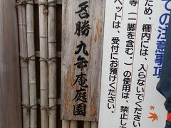 　仁比山神社仁王門をくぐり抜け、坂の参道を上ぼりつめると、その左手には緑の生け垣に囲まれた風雅な葦葺の屋根が見えます。そこが旧伊丹家住宅、通称「九年庵」です。　
　名勝九年庵庭園への入口です。素朴な表札が掛かっていました。