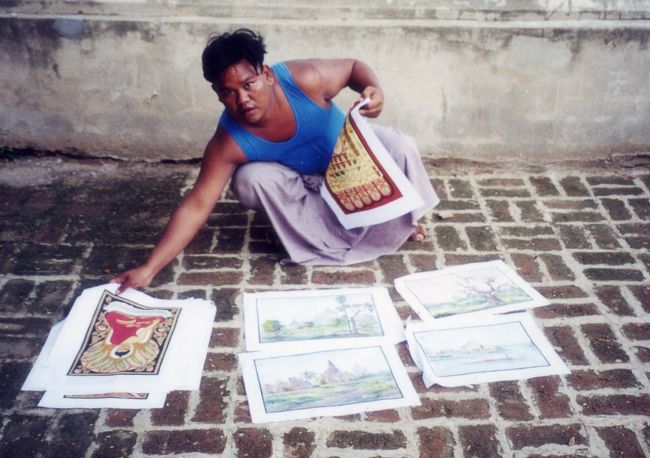 「マヌーハ寺院」は仏像を彫った後に、それをかぶせるように寺院を建てたそうだ。中には四体の仏像が院内の空間を埋めるように安置されていた。三体の座像は「生」が囚われの身のように不自由なものであること、涅槃像は死してこそ生の苦しみから解放されるのだという事を示しているという。<br /><br />マヌーハ寺院境内で、パガンの絵を売っていた。彼の兄が描いたという。タビィニュ寺院の水彩画を１枚記念に買った。<br />