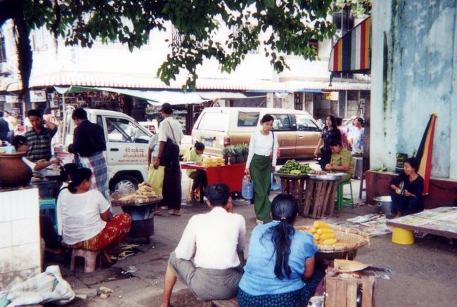 昼からは「ボジョーアウサンマーケット」と「チャィナタウン」を散策した。<br />マーケットでは、流行っている音楽テープ店を、店員の薦めで買った。全部ミャンマー語表示なので歌手名も特定できない。映画館ではタイタニツクがかかっていたが、ディーダは「濡れ場はカットされているのよ。」と。<br />路上には、あらゆる種類の屋台が並んでいた。食物・衣服・道具類なんでもそろう。<br />冷水屋もあった。50㎝ほどの針金の3か所に輪があり、それに菱形の氷が付けられている。注文が入ると、水をコップに入れ一番上の氷にかけると、残り2つの氷の表面にも水が流れ、下で受けた時には冷えているという訳だ。美人系の売り子の所にやはり沢山の客がいた。<br />タバコはバラ売りが当たり前のようだ。１本買い、そこにぶら下がっているライターで火をつける。<br /><br />「クーン屋」(噛み煙草屋)もあちこちで店を出していた。<br />ビンロウの種と石灰をキンマの葉で包んで噛むと、口がしびれような清涼感がいいらしい。口の中を赤く染めて噛んでいる男が、道路のあちこちに吐き捨てるものだから、道路にも赤く染まる。試してみたくてディーダに「やってみたい。」と言ってみたら、絶対していだめ!!。と強く言われた。<br />　街のそぞろ歩きはとても楽しい。気温もそれほど高くない30度程だろう。チャィナタウン界隈の活況はすごかった。インド系の男がルビーやいかがわしいクスリを買わないかとすり寄って来る。宝くじをやっていたが、1等賞品はセコハンパジェロだった。道路には車がひしめき、超満員の乗り合いバスやトラックが行き交っている。車の後ろにも5,6人がしがみついている。自転車の横にサイドカーを付けた「サイカー」も健在だ。<br /><br /><br />※これはホテル近くの街角の一枚<br />