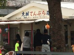 知人(沖縄県民)が利用するのは、こちらのお店。
中本鮮魚店から右方向に進むと、左手に出てくるのが大城てんぷら店。
この前には、地元車がいっぱい停まっています。
最近「れ」「わ」ナンバーも増えていますが、兎にも角にも中本鮮魚店の方はガイドブックなどの影響もあるのか観光客だらけ。
そして、こちらの大城てんぷら店は地元民が多い。
これが今の奥武島の様子です。