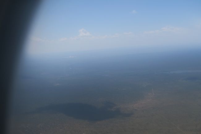 来ましたー、ヴィクトリアフォールズ。飛行機から水煙が見えると聞いていたので窓側にしたのですが、見えましたー！機内中テンションが上がります。<br /><br />定刻より10分早く着陸しました。天気も快晴。<br /><br />ジンバブエはビザが必要です。と言っても事前に取るわけではなく、空港到着してから申請します。ツアーで行くと事前に用紙をいただけるかもしれませんが、私は持っていません。まず、用紙を手に入れる必要があるのですが、道すがら置いてありません。通路は申請する人の行列で、すごい人だかりです。その人だかりを掻き分けて進み、用紙を手に入れ、また逆走して列の最後尾に並びました。手前に用紙を置いておくか機内で配ってほしい。入国カウンターに並ぶ前に書類のチェックをしてくれる人がいます。カウンターで揉めないのでいいシステムです。書類チェックの人に何ビザがいるんだ？と聞かれます。<br />ビザには幾つか種類があります。<br />・シングル　有効期間中(30日)に1回のみ入出国が可能　：US$30<br />・ダブル　有効期間中(30日)に2回の入出国が可能　：US$45<br />・マルチプル　有効期間中(30日)に何度でも入出国が可能　：US$55(※入国管理事務所でのみ取得できる。)<br />・KAZAビザ　有効期間中(30日)であればジンバブエとザンビアの双方を行き来可能　：US$50<br /><br />私はボツワナやザンビアに行く予定なので何度かジンバブエに入国します。というわけでKAZAビザを申請。係りの方が赤ペンで大きく”K”と用紙に記載して何番に並んで、と教えてくれます。書類のチェックを受けるまでに10分並び、カウンターに到達するまでに20分並び、計30分は並びましたね。<br />思い返してみれば今回の旅は並んでばっかりだったなぁ。この後も各所で行列に並ぶことになります。