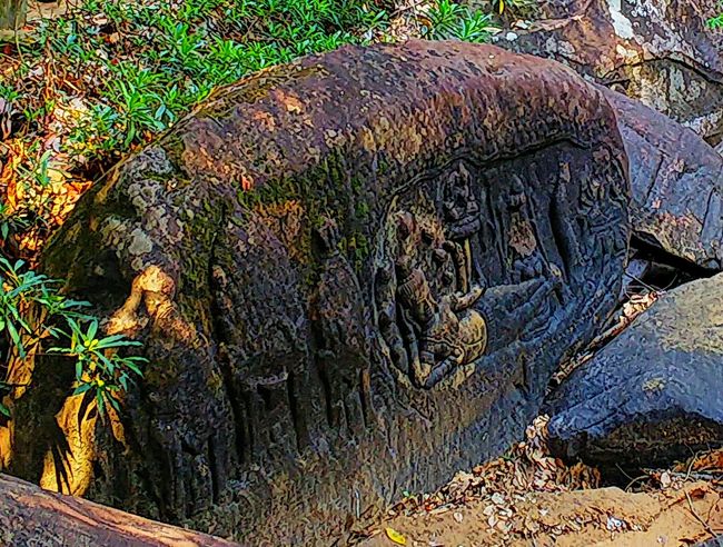 ヴィシュヌ神がヘビ神の上に横たわってくつろぎ、足元には女神が、ハスの花の上にはブラフマー神がいる彫刻。