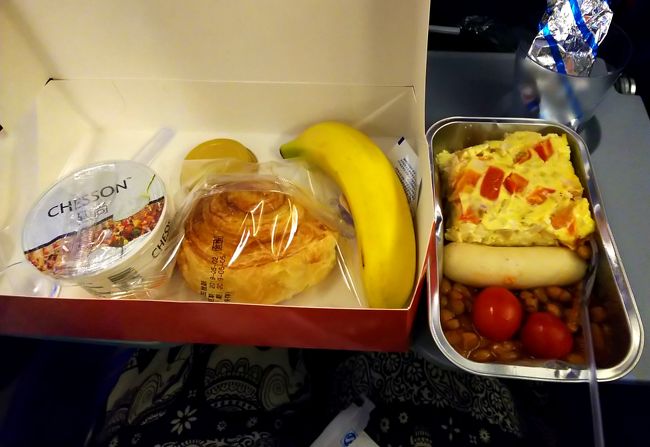 機内食は、シーフードヌードルと、ソーセージだと言うので、ソーセージを頼んでみたら、こんなのが来ました。<br />うーん…(-ω-；) かなりビミョー。豆腐入りの卵焼き的なオカズもメインの白いソーセージも、…って感じ。パンとバナナは、フツーに美味しかったですけどね(^_^;)
