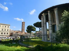 ヘラクレス神殿(Tempio di Ercole Vincitore)とサンタ・マリア・イン・コスメディン教会(Chiesa di Santa Maria in Cosmedin)

真実の口広場より。
右端に見える、円形の20本のコリント式の大理石の支柱に囲まれたヘラクレス神殿。昔は、フィロ・ロマーノにある古代ギリシアのかまどの神様を祭るヴェスタの神殿と似ており、同じくヴェスタの神殿と呼ばれていましたが、大理石に刻まれた献辞からこれが征服者ヘラクレスに捧げられた神殿であることが判明。またこの場所は畜産業者が集まる市場、フォロ(Foro Boario)があったことからも、家畜の守り神でもあるヘラクレスに捧げられた神殿と考えられます。ローマに残る大理石の神殿としては最も古いとのこと。紀元前2世紀終わり。

ということで、この場所は、地球の歩き方では、ヴェスタの神殿、４トラでは、ヘラクレス神殿、グーグルでは、フォロ・ボアリオ(Foro Boario)とも表現されています。

ウェスタ【Vesta】古代ローマ神話のかまどの女神。神像はなく、火が崇拝対象とされる 。家庭のみならず国家のかまどの神としてローマのウェスタの神殿に聖火が燃え続け、 清純な女性の祭司たちによって守られた。ギリシャ神話のヘスティアと同一視される。