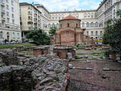 四方をビルに囲まれてポツンと建つ、聖ゲオルギ教会。教会の手前にあるのはローマ時代の浴場跡。