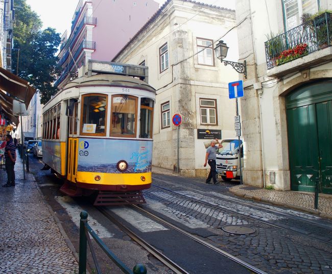 ここでリスボンの地形を説明すると、さきほどのコメルシオ広場とアウグスタ通りあたりを中心にした扇状地みたいなすり鉢状になっている。しかも結構な傾斜だ。つまりどこへ行くにも坂を上らなければならない。<br />時折狭い坂道をトラムが行き交う。なかなか趣深い情景だ。<br />ーーー暑くなければ。<br />「あっつーーー。」<br />「言わない！余計暑い！」<br />「もう歩きたくないよー」<br />娘も半べそ状態だ。<br />「もうすぐそこだから。。」<br />しかし、たどり着いたレストランに入ると<br />「え？１２時からだけど？」<br />と普通に言われた。<br />「ええ、１０時からって書いてあるけど」<br />「いやいや、今日は１２時ね。」<br />てきとーー！？<br />「どうする？」<br />「こうなったらこの上の展望台まで歩こう！」<br />「いやあーー！？」<br />娘が泣いたのは言うまでもない。