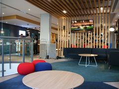 (外観を取り忘れました。)
ホテルは「ホリデイインエクスプレス　ジブラルタル」。ここに２泊します。
ロビーはポップでカジュアルな感じです。

ここを選んだ理由は
・ジブラルタルのホテルは総じて高い。
・家族向けの部屋があるホテルが見つからない。
・スペイン側のラ・リネアに行けば見つかるものの
　ジブラルタルまで徒歩20分なのと治安が若干不安。
・窓から滑走路が見える。
・オープンしてから間もない
・周りのホテルに比べて値段相応

つまり、最後の３点＋消去法で選びました。

予約した部屋はツイン＋エクストラの３人部屋。
４人部屋の設定はなかったのですが、これまで３人部屋であっても、子どもが小さいので添い寝であればスルーしてくれるだろう、と思っていました。・・・が、

「No」
「添い寝でも？」
「No」
あっさりチェックインを拒否されました。ジブラルタルの法令が厳しいのか冷淡な感じのマネージャー氏が応対したからかは分かりませんが、規約の壁に阻まれました。

応対が冷淡マネージャーから若いお姉さんに代わり、チェックイン手続き続行。コネクションルームかつ滑走路側の部屋を希望し、ダブルルームとツインルームがつながった部屋をアサインしてもらいました。

ただ、想定はしていたとはいえ、２泊の宿泊代は約\24,000から約\53,000に。。。