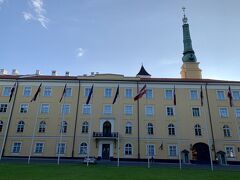 18:54国旗が掲揚されている立派な黄色い宮殿のような建物が。広場は『ピルス広場』、建物は『リーガ城』