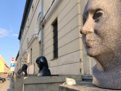 19:04トゥァルニャ通り、『アルセナール展示ホール』前の、顔の像の前を通って。偉人達の顔が並びます。