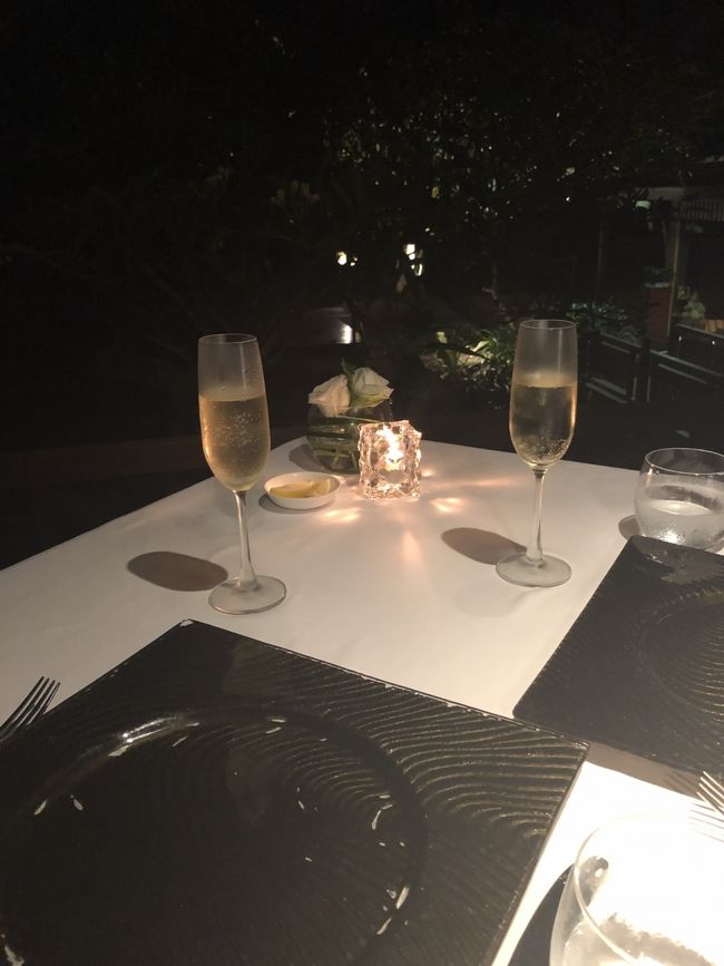 予約したのはアウトサイドの席です。思った以上に暗くてあまり景色は見えませんが、目の前はプライベートビーチです。暑そうだけど、昼間の方が眺めはいいかも。<br />カンパイはシャンパンで♪<br />ワインはペアリングもできますが、今回は白のボトルにしました。ボトルは１万円くらい～だったと思います。