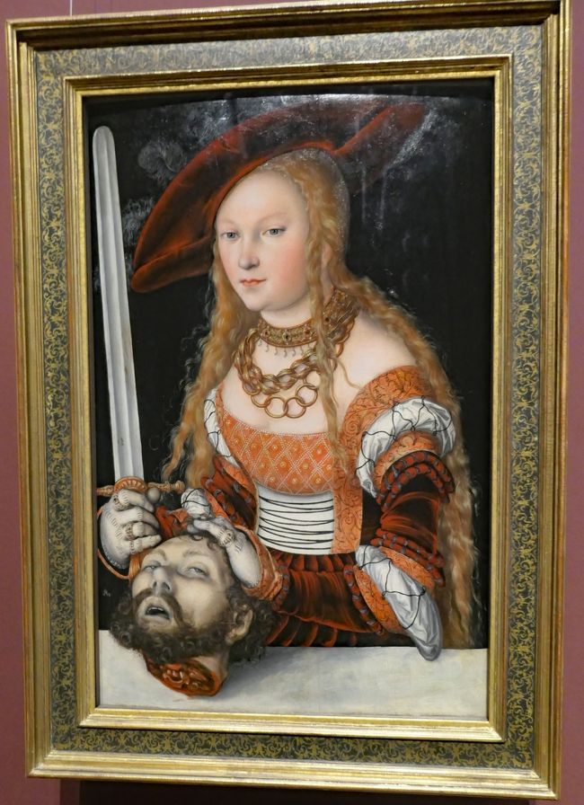 「ジュディスとホロフェルネス, Judith and Holofernes」と題する絵で、ルーカス・クラナッハ（Lucas Cranach der Ältere、1472 - 1553)が1530年に描いたものです。<br />ジュディスによるホロフェルネスの斬首は、キリスト教に関連する「ジュディスの書, Book of Judith」に書かれている物語で、ルネサンスおよびバロック時代の多くの絵画や彫刻の主題にされています。美しい未亡人であるジュディスが貞節を守るため、彼女を自分のものにしようとしたアッシリアの将軍ホロフェルネスを殺害した様子を描いたものです。殺害後にも拘わらずジュディスの表情がにこやかで美しく描かれているのは、貴族向けの宗教画の特長であるように思います。