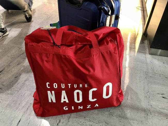 こちらはドレスバッグです。衣装合わせをしていくなかで、現地に用意がないデザインやサイズに決まった場合は日本からの持ち込みになります。<br />成田空港のJAL ABCカウンターに予めサロンから送られているので、当日ピックアップし、自分の手荷物としてバリに持っていきます。<br />打ち合わせの段階ではダンボールでの受け取りで預け荷物と言われたのですが、こればっかりはロスバゲが怖いので、お願いしてこちらのバッグにしてもらい、機内に持ち込みました。重さは思ったよりも軽かったです。<br />なお、購入した新郎のウイングシャツと白靴下も同梱されてます。