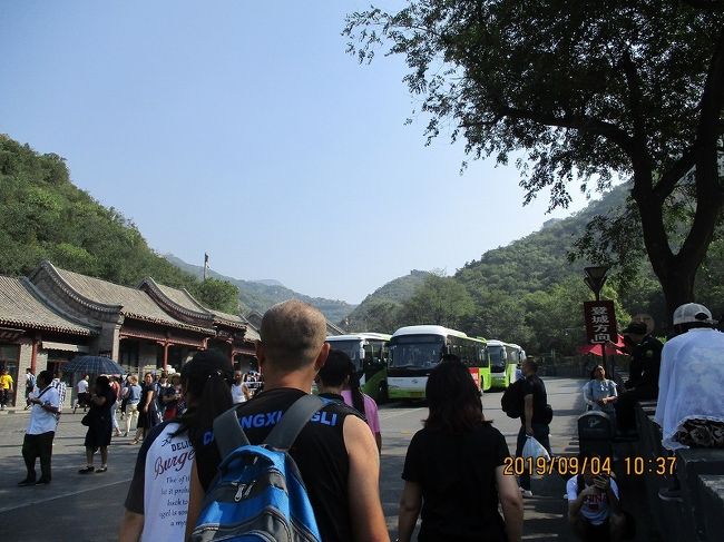↑ 長城・八達嶺のバス停留所着。<br />（注：八達嶺駅とは「居庸外鎮」門を挟んで反対側。「熊楽園」の前。）。<br />　１時間少し前に北京市内の地下鉄積水潭駅近くのバス乗り場（徳勝門箭楼）から公共バス（８７７路・１２元）に乗り、到着。<br />　バスを降りると金髪をはじめアジア以外の方たちが目立ってきた。<br />ーーーーーーーーーーーーーーーーーー<br />　（余談）ここまでの足取りでは若干の「疲れ」も。<br />　バス乗車前、地下鉄駅で目についた案内なりにゆくと、B2出口からいったん運河沿いに徳勝門北橋まですすんでしまい、駅出口から見えていた箭楼まで引返してくるという順路を辿った。<br />　大きな道路を挟んで駅とバス乗り場があるのでこうなるんだけれど、土地柄か、交通量の多い道路を歩いて横切る人もいる。<br />　バス乗り場では八達嶺長城行のバスがズラリと並んでいて、一台ずつ、満員になる都度順番に発車しているので発車待ちの一台に跳び乗る。<br />　最後の座席に潜り込めてよかったー・・・と思いきや、３人がけの座席の真ん中の席。<br />　だけならまだよかったが、両側の御仁は１．２（？）人分くらいの幅のある年配の男女。出発してしばらく、この男女が話し始めたので否応なく耳に入ってくる会話からすると、夫婦らしい。なんでこんな座り方しているんでしょうね？