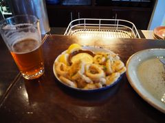 　街に戻り、ホテル近くのレストラン「Public Kitchen & Bar」にやってきました。カウンター席に案内されました。旅行期間中は、前菜、肉料理、サラダ＋飲み物で攻めたいと考えていました。ビール飲みかけで恐縮ですが、この「イカのリングフライ」は最高！