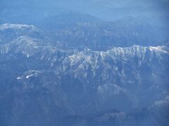 座席は右座席、瀬戸内海上空を航行しています。右側には四国山地が見えてきました。
この状態なら西日本最高峰の石鎚山（1982m）が見えるでしょう。
3月ですが四国の高峰は冠雪していました。一番雪を被っているのが石鎚山だろうと予想をつけて、それらしき山をカメラで追いました。
左端の中央に成就社や山小屋と思しき建物が見えるので写真中央の山が石鎚山と思われます。高い山なので雪を被っていると思いましたがそうでもないようです。
