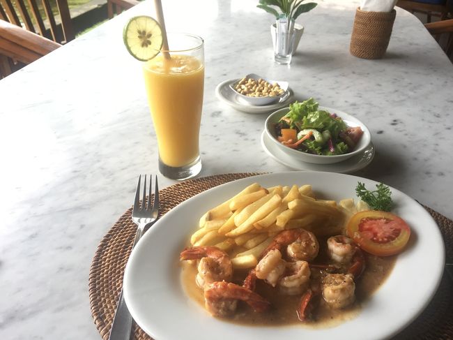 マンゴージュースとガーリックプラウン。<br />サラダが付いてくるんですがこれがすごく美味しかった。カフェ・ワヤンは行ったことがなかったけど美味しいのでしょうね。<br />マンゴージュースも、海老もポテトも美味でした。10分もせずにぺろり。トータルRp 120000くらい。<br /><br />家族連れはシンガポール人かな？<br />料理が来てもずっと敷地内で撮影大会しててドン引きしつつ観察してました。