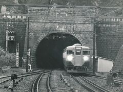 国鉄時代1967年の丹那トンネル入口（来宮口）
まだ縦書きの木製トンネル標で「丹那隧道」と書かれていることがわかります。
上部には鉄道大臣･内田信也揮毫の「丹那隧道」の扁額があります。
当時丹那トンネルは東京鉄道管理局（東鉄）の所管で、JR化後に境界が函南口から熱海口に変更され、トンネルはJR東海の所管に変わりました。
大目玉の111系が懐かしいですね。
【５－１】
