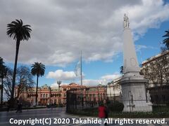 五月広場(Plaza de Mayo)

右側に立つのが五月革命(Revolución de Mayo)１周年を記念して広場中央に建てられた五月の塔(Pirámide de Mayo)、奥が大統領官邸(Casa Rosada)です。


五月広場：https://en.wikipedia.org/wiki/Plaza_de_Mayo
五月の塔：https://en.wikipedia.org/wiki/Pirámide_de_Mayo
大統領官邸：https://ja.wikipedia.org/wiki/%E3%82%AB%E3%82%B5%E3%83%BB%E3%83%AD%E3%82%B5%E3%83%80