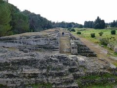 12月30日
カターニャ空港から車で1時間ほど走って、シラクーサの町に到着しました。町の西方にあるネアポリス考古学公園を訪問しました。ギリシャ、ローマ時代の遺跡が多く残されています。

公園入口にある「イエロンII世の祭壇, Altar of Hiero II」で、紀元前3世紀にイエロンII世王が作ったものです。幅22ｍ、長さ198mもあり、古代に建造された祭壇のなかで最大だそうです。オリンピアのゼウス神のお祭りで使用されました。