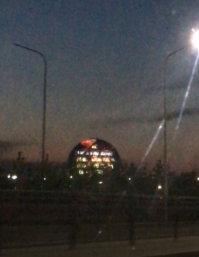 アスタナの空港には万博時の同僚でスケオタの子が迎えに来てくれていました。北京からの同じ便に今回のショーに出演する織田信成さんが乗っていました(そのため、彼はサイン会は不参加)。迎えに来てくれた子からLINEで「織田くん乗ってたよね？私の隣に彼のお迎えのスタッフがいていつ出て来るのって聞いてる」「今荷物ピックアップしたからもうすぐ行くと思うよ～」「出てきた、写真撮って貰っちゃった」などと実況していました(笑)。なお彼女はサイン会行ってから空港に直行してくれていて、サイン会でカリナちゃんと知り合ったそうです。<br /><br />アスタナではこの同僚の所に、同じく万博の同僚でアルマトイに留学中の子がこのショーのために来ています。私の少し後の便で、数日前にカザフ入りしてアルマトイに滞在していたデニスファンの万博同僚(https://4travel.jp/travelogue/11626465)が来るのでその子の到着を待って、４人で家に向かいました。<br /><br />空港から街へ向かう途中に光るカザフスタン館の球。ああ懐かしい！カザフ語で「素晴らしい」のことを「タマシャ」というので球にかけて連発します。