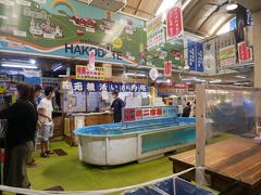 そんな中「いか釣り」の看板につられて行ってみると市場の中にイカ釣り広場（←勝手に命名）が。
釣りたてのイカをさばいてイカ刺しで食べさせてくれるみたいだけど…朝ご飯がイカ刺しだけではちょっと足りない…。
アトラクション的な感じで面白いとは思うけど。
定食みたいなのないのかな？
と思いつつもちょっと見学。
すぐ釣れるのかと思いきや挑戦中のお兄ちゃんはなかなか苦戦しつつもイカを釣り上げていた。
ちなみにイカ釣りの料金は時価でこの日は1匹1300円。