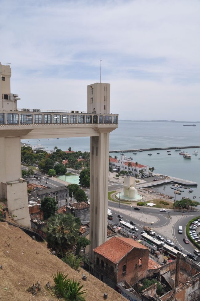 サルバドールのセントロは丘の上にあるので隣接する港とはエレベーターとケーブルカーで結ばれている。かなりの高低差がある。これらの交通機関は市民の生命線なので安い値段設定で１回１センターボ（２円）だ。港周辺には土産物屋の市場があり観光客が多い。しかし海は異臭が満ち汚い。<br /><br />柱のみたいなのがエレベーター。