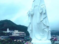 神の島の岸壁に佇むマリア様と、左奥にカトリック神の島教会。