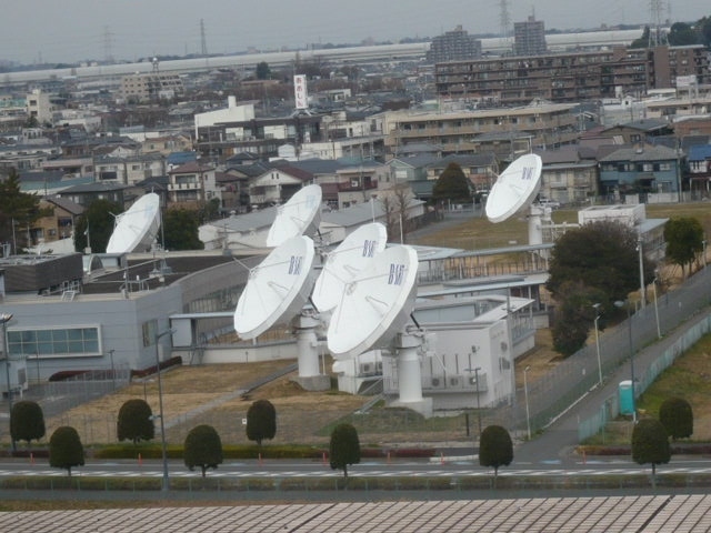 今回訪れた川口の放送衛星管制センターのアンテナです。<br /><br />背景の遠くに、ほぼ東西方向に走る外環自動車が見えます。<br /><br />放送衛星管制センターのパラボラアンテナは、ボルネオ島の赤道上空の放送衛星を睨んでいます。(南西の方向です。)